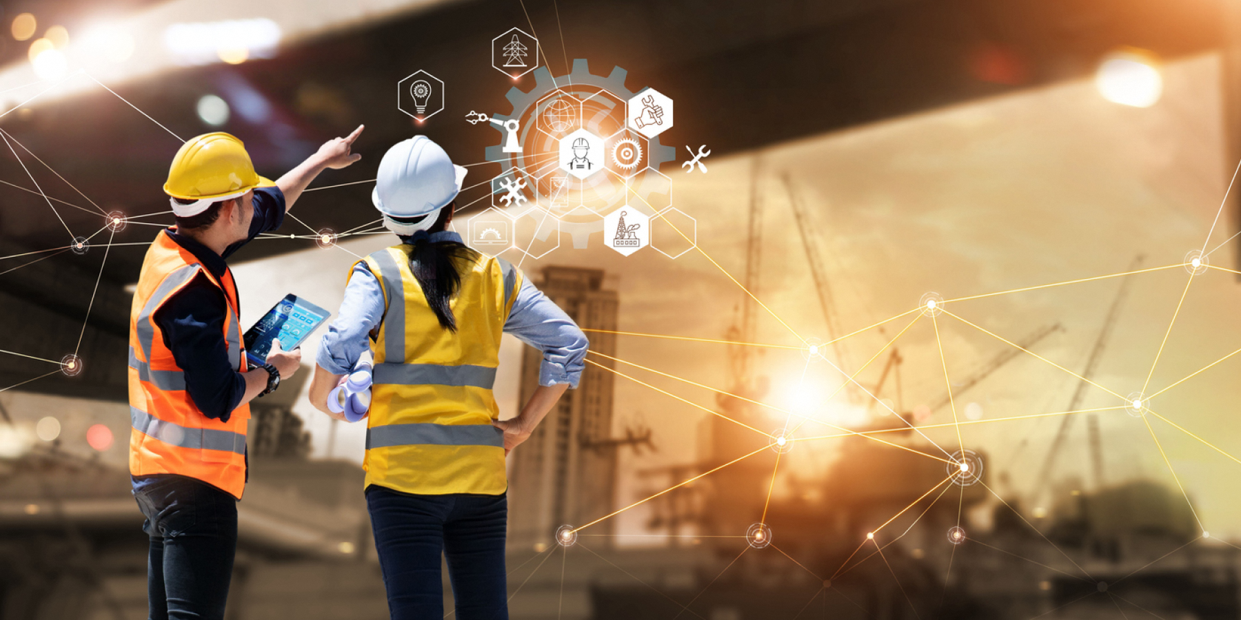 worker in safety gear using a laptop at a construction site.